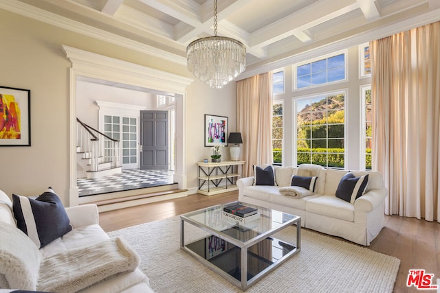 living room featuring crown molding, hardwood / wood-style flooring, coffered ceiling, and an inviting chandelier