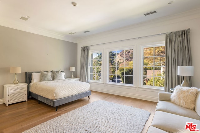 bedroom featuring light wood-type flooring and crown molding