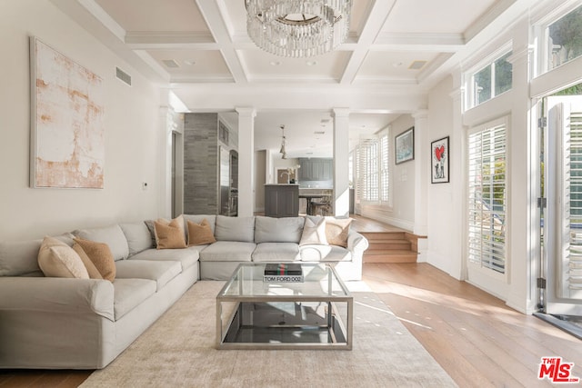 living room featuring ornate columns, coffered ceiling, beamed ceiling, a chandelier, and ornamental molding