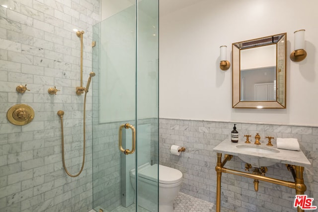 bathroom with tile walls, toilet, walk in shower, and sink