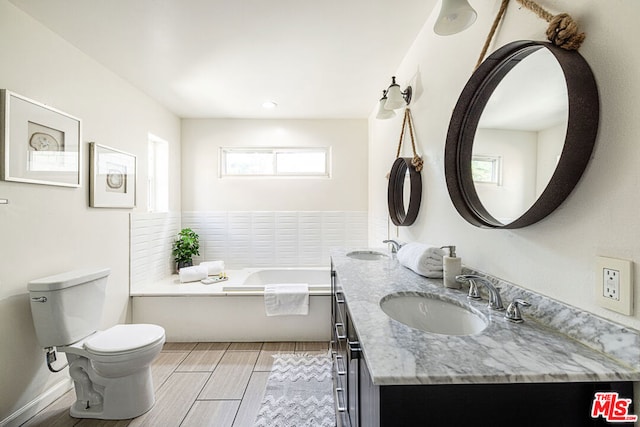 bathroom featuring a bath, vanity, toilet, and plenty of natural light