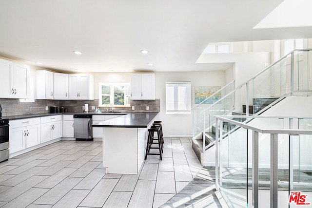 kitchen with white cabinets, sink, a breakfast bar area, a kitchen island, and stainless steel appliances