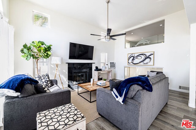 living room with a tiled fireplace, ceiling fan, and hardwood / wood-style flooring