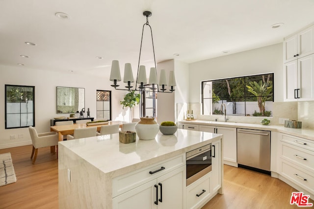 kitchen with built in microwave, pendant lighting, dishwasher, a center island, and white cabinetry