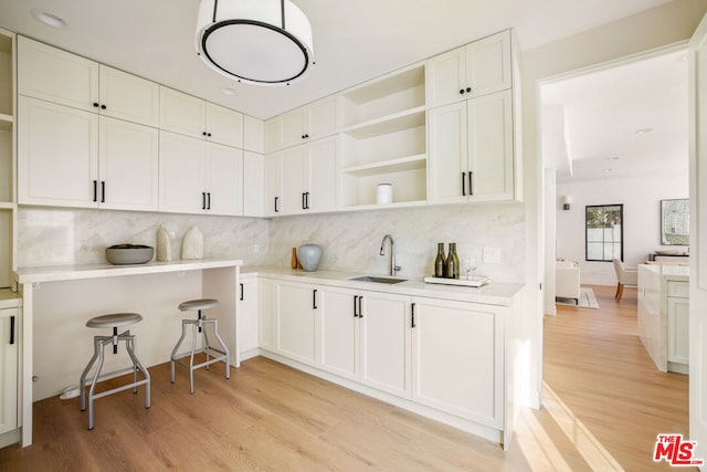 kitchen with light wood-type flooring, white cabinetry, sink, and tasteful backsplash