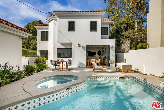 rear view of property featuring a pool with hot tub and a patio