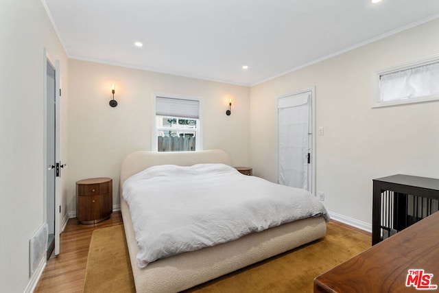 bedroom with light wood-type flooring and crown molding