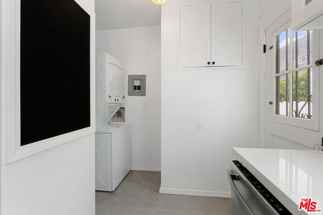 laundry area featuring stacked washing maching and dryer, a healthy amount of sunlight, and light tile patterned flooring