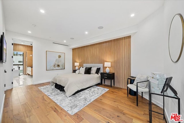 bedroom with wooden walls and light hardwood / wood-style floors