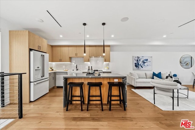 kitchen featuring high end white refrigerator, decorative light fixtures, light hardwood / wood-style flooring, dishwasher, and a kitchen island