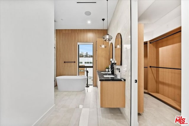 bathroom featuring vanity, a tub to relax in, and wooden walls