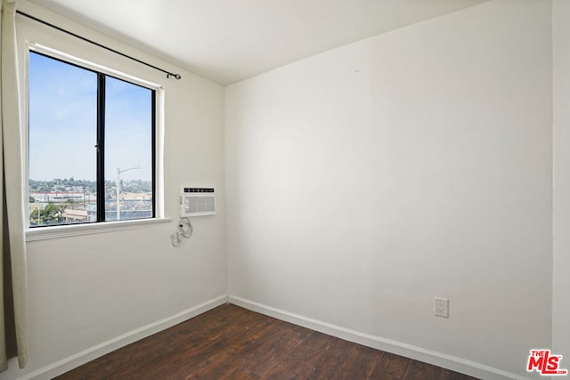 unfurnished room with a wall unit AC and dark wood-type flooring