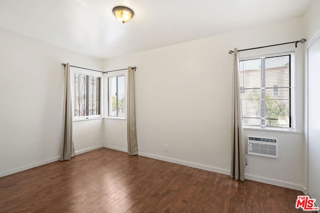 empty room with dark hardwood / wood-style flooring and a wall mounted air conditioner