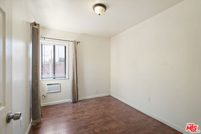 spare room with dark hardwood / wood-style floors and a wall unit AC