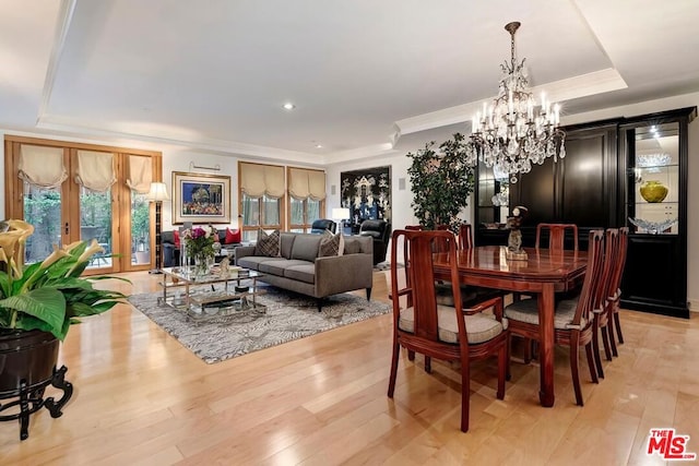 dining area with an inviting chandelier, light hardwood / wood-style floors, a wealth of natural light, and a tray ceiling