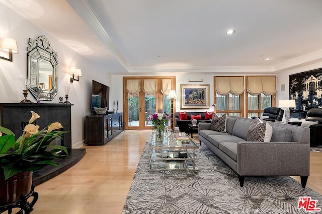 living room featuring french doors, light wood-type flooring, a tray ceiling, and a wealth of natural light