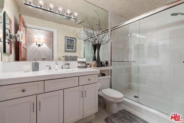 bathroom with an enclosed shower, vanity, and toilet