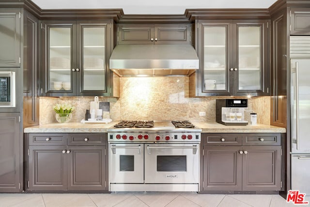 kitchen with built in appliances, decorative backsplash, dark brown cabinetry, and light tile patterned floors