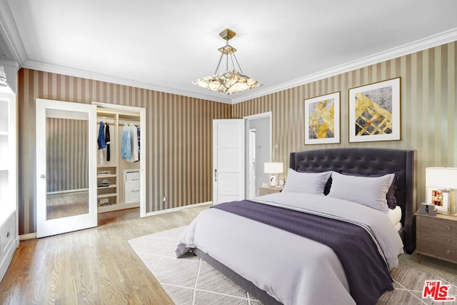 bedroom featuring hardwood / wood-style flooring, an inviting chandelier, crown molding, and a closet