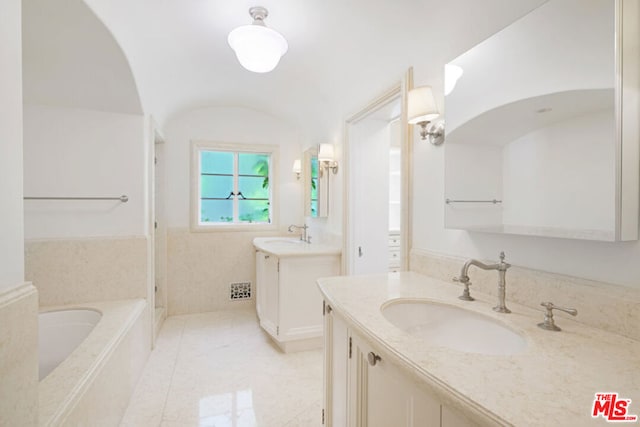 bathroom with tile patterned floors, vanity, vaulted ceiling, and a bathing tub