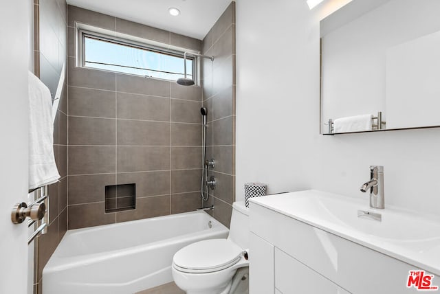 full bathroom featuring vanity, tiled shower / bath combo, and toilet