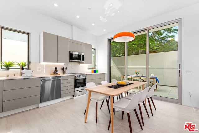 kitchen featuring gray cabinetry, a wealth of natural light, hanging light fixtures, and appliances with stainless steel finishes