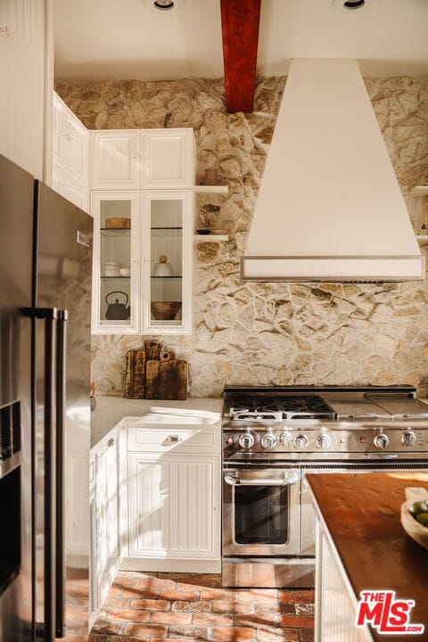 kitchen featuring ventilation hood, white cabinetry, beamed ceiling, and appliances with stainless steel finishes