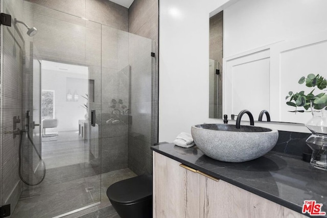 bathroom with vanity, toilet, and a shower with door