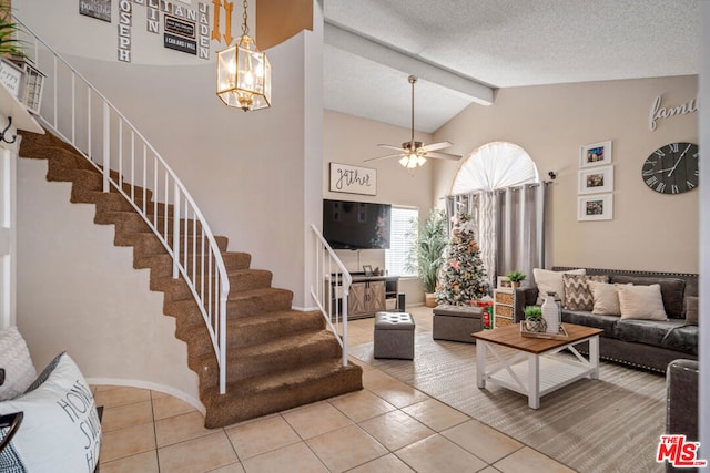 living room featuring vaulted ceiling with beams, ceiling fan with notable chandelier, light tile patterned floors, and a textured ceiling