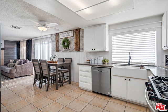 kitchen featuring sink, a textured ceiling, appliances with stainless steel finishes, light tile patterned flooring, and white cabinetry