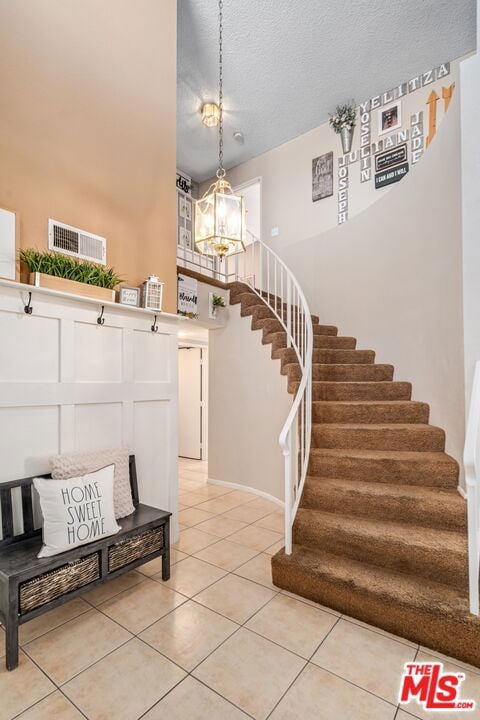 tiled foyer entrance featuring a notable chandelier and a textured ceiling