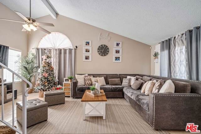 living room featuring vaulted ceiling with beams, ceiling fan, and a textured ceiling