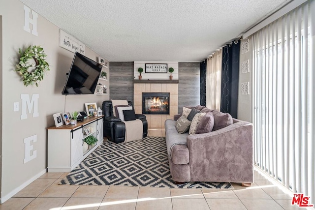 living room featuring a tile fireplace, light tile patterned floors, and a textured ceiling