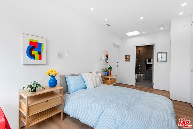 bedroom featuring connected bathroom and wood-type flooring