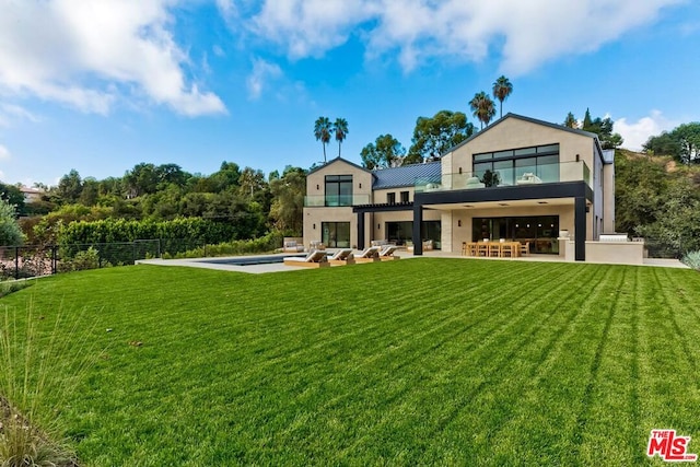 rear view of property featuring a bar, a patio, a balcony, and a lawn