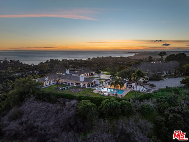 aerial view at dusk featuring a water view