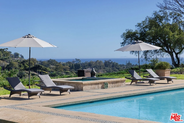 view of pool featuring a patio area, an in ground hot tub, and a water view