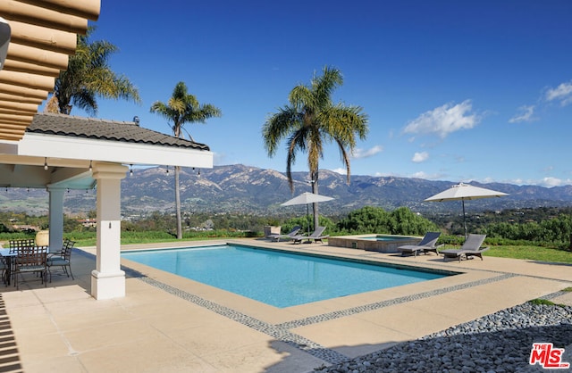 view of swimming pool featuring an in ground hot tub, a mountain view, and a patio