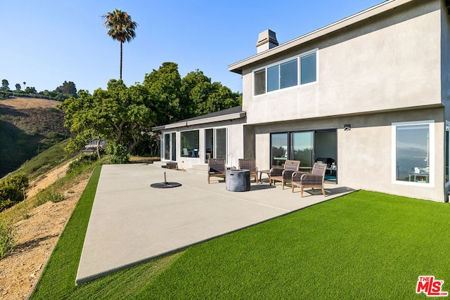 back of house featuring a yard, an outdoor fire pit, and a patio area