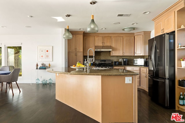 kitchen featuring appliances with stainless steel finishes, dark hardwood / wood-style flooring, sink, decorative light fixtures, and an island with sink