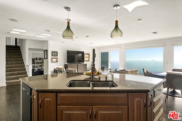 kitchen featuring sink, dishwasher, dark wood-type flooring, decorative light fixtures, and a kitchen island with sink