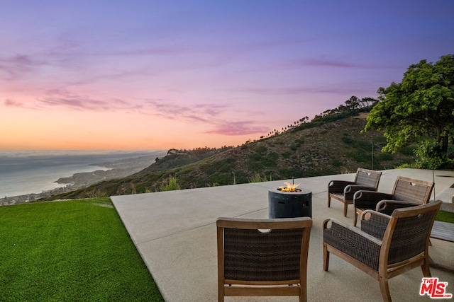 patio terrace at dusk with an outdoor fire pit and a water and mountain view