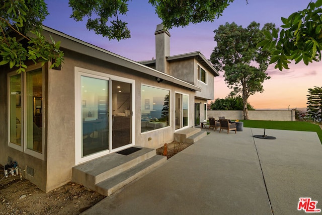 back house at dusk with a patio and an outdoor hangout area