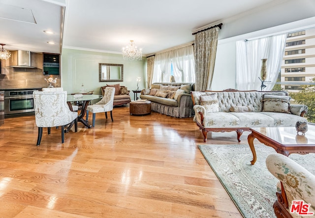 living room featuring light hardwood / wood-style floors, ornamental molding, and a chandelier