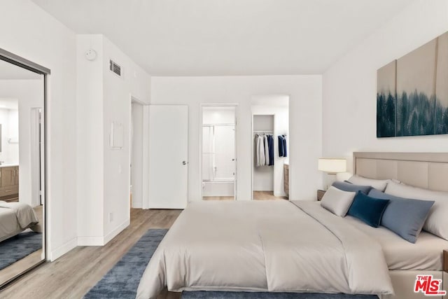 bedroom featuring a spacious closet, ensuite bathroom, light hardwood / wood-style flooring, and a closet