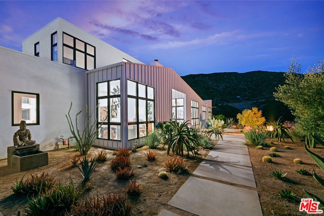 property exterior at dusk with a mountain view