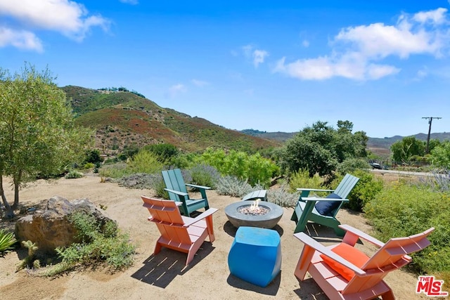 view of patio with a mountain view and an outdoor fire pit