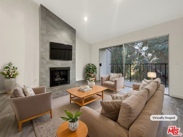 living room featuring a tile fireplace, lofted ceiling, and hardwood / wood-style flooring