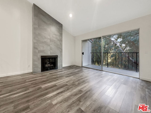 unfurnished living room featuring a tile fireplace, hardwood / wood-style floors, and vaulted ceiling