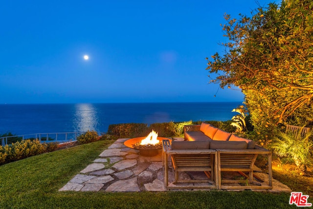 view of patio with a fire pit and a water view